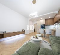 NOVO ZREKONŠTRUOVANÝ 4-IZBOVÝ BYT V TICHOM PROSTREDÍ - 78 m² - NOVÉ ME - Obývacia izba v 4-izbovom byte s pohovkou a podlahou s dreveným dekorom.