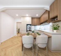 NOVO ZREKONŠTRUOVANÝ 4-IZBOVÝ BYT V TICHOM PROSTREDÍ - 78 m² - NOVÉ ME - Kuchyňa v 4-izbovom byte s podlahou s dreveným dekorom a moderným nábytkom.
