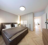 NOVO ZREKONŠTRUOVANÝ 4-IZBOVÝ BYT V TICHOM PROSTREDÍ - 78 m² - NOVÉ ME - Spálňa v 4-izbovom byte s podlahou s dreveným dekorom, svetlým nábytkom a rastlinou.