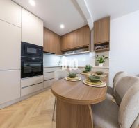 NOVO ZREKONŠTRUOVANÝ 4-IZBOVÝ BYT V TICHOM PROSTREDÍ - 78 m² - NOVÉ ME - Kuchyňa so vstavanými spotrebičmi a jedálenským stolom v 4-izbovom byte, podlaha s dreveným dekorom.