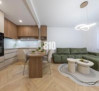 NOVO ZREKONŠTRUOVANÝ 4-IZBOVÝ BYT V TICHOM PROSTREDÍ - 78 m² - NOVÉ ME - Kuchyňa v 4-izbovom byte s podlahou s dreveným dekorom a zelenou sedačkou.