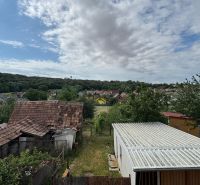 NA PREDAJ poschodový Rodinný dom v Jarku - Pohľad z rodinného domu v Jarku na záhradu, strechy a lesnatú krajinu.
