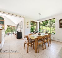 SÚKROMNÉ SÍDLO NA KONCI KÚPEĽNÉHO PARKU | 4 454 m² | TRENČ. TEPLICE - Jedáleň v rodinnom dome s keramickou pecou, veľkými oknami a dreveným jedálenským stolom.