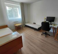 Na prenájom - Zariadený 3 izbový byt na Lipovci so záhradou - Izba v 3-izbovom byte s posteľou, stolom a podlahou s dreveným dekorom.