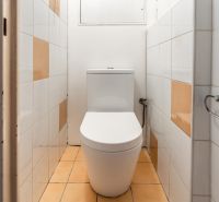  3-izbbyt s veľkou loggiou vo vyhľadávanej lokalite Bratisl - Kúpeľňa v 3-izbovom byte s bielym toaletou a dlažbou s oranžovými prvkami.