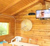 PREDAJ - Záhrada v lokalite Devínskej jazero - Drevený interiér s televízorom, stolom a plastovou stoličkou v Záhradách.