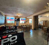 Obchodný priestor s ubytovacím zariadením - Interiér gastro priestorov s dreveným dekorom a slovenskými vlajkami na stenách.