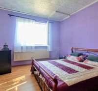 5-IZBOVÝ RODINNÝ DOM V OBCI TRHOVIŠTE  PRI MICHALOVCIACH - Spálňa s fialovými stenami, posteľou, tmavou komodou a podlahou s dreveným dekorom.