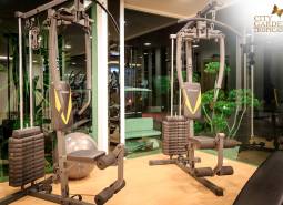 Fitness vybavenie vo výstavbe bytov, zelené prvky, osvetlenie a zrkadlové steny.