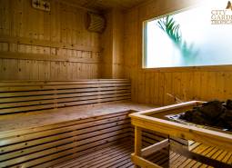 Drevená sauna s preskleným oknom a logom realitnej kancelárie.