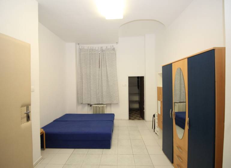 Dáme do prenájmu 1-izb.byt priamo v centre na Gorkého ul.cena vrátaneE - Svetlý 1-izbový byt s modrou posteľou, šatníkovou skriňou a bielou dlažbou.