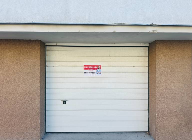 (16 m²) GARÁŽ NA PRENÁJOM V CENTRE - Biela garážová brána na Štefánikovom námestí v Spišskej Novej Vsi s nápisom na predaj.