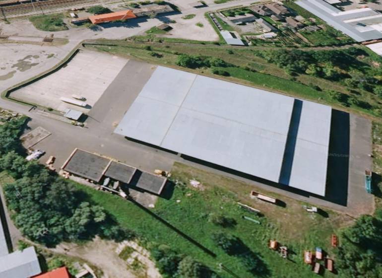 Skladový areál, Pribeník - Letecký pohľad na sklady a haly v Pribeníku so zeleňou naokolo.