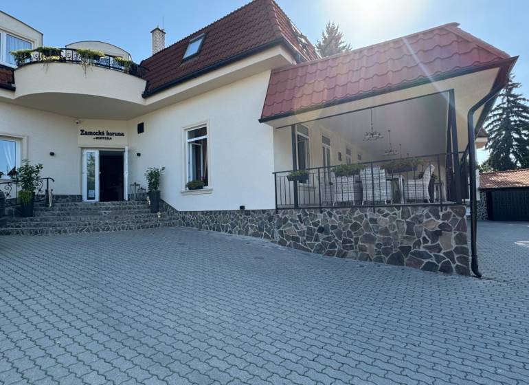 NA PREDAJ hotel s reštauráciou - Pohľad na budovu obklopenú zelenou, hotely ponúkajúce ubytovanie na nádvorí.