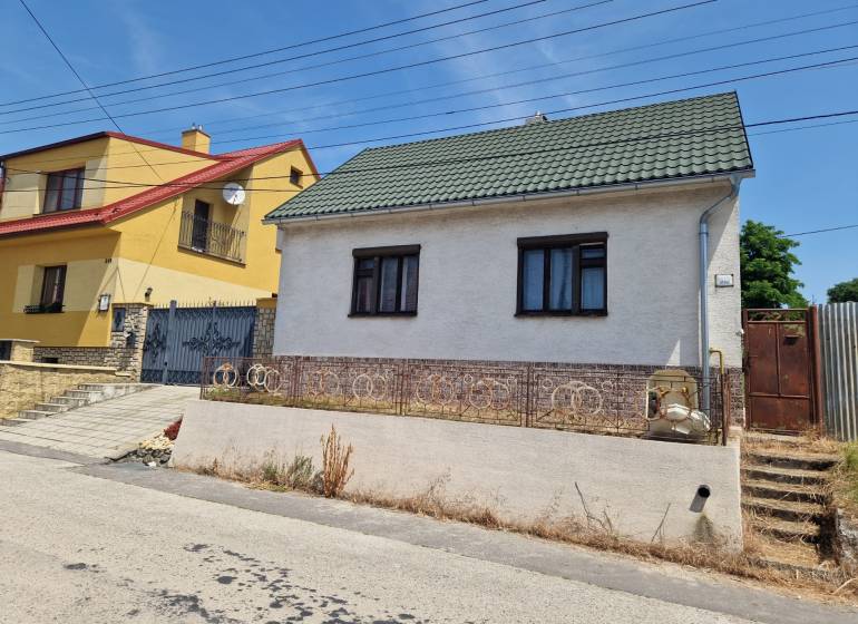 NA PREDAJ RODINNÝ DOM V OBCI ŠTEFANOV, OKRES SENICA - Rodinný dom v Štefanove s bielou omietkou a zelenou strechou na tichej ulici.