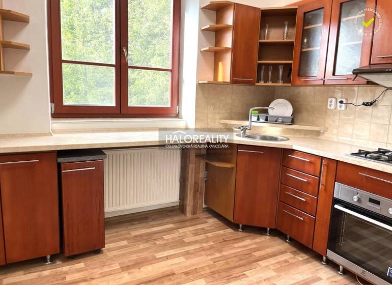 Predaj, trojizbový byt Michalovce - Kuchyňa v 3-izbovom byte s drevenou linkou, okno s výhľadom do zelene.