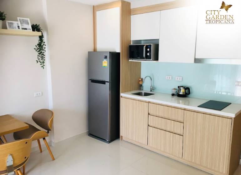 1 IZBOVÝ APARTMÁN (1 SPÁLŇA + 1 OBÝV. IZBA) CITY GARDEN TROPICANA  - Kuchynský kút v 2-izbovom byte s chladničkou, mikrovlnkou a dreveným nábytkom.
