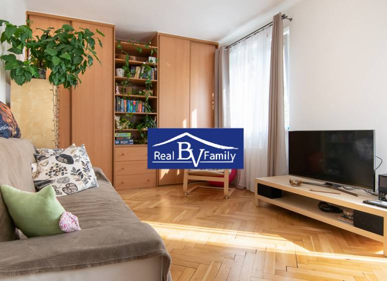 PRENÁJOM, STROMOVÁ, NOVÉ MESTO - DVOJGARSÓNKA - Obývačka v dvojgarsónke so sedačkou, televízorom a veľkou skriňou, svetlé drevené parkety.