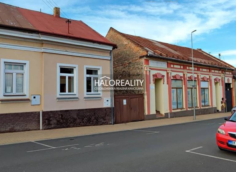REZERVOVANÉ - Predaj, rodinný dom Lučenec, centrum -... - Rodinný dom v Lučenci so staršími fasádami a zaparkovaným červeným autom na ulici.
