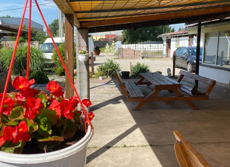 Penzión s 13 izbami na predaj, Dunajská ul., Tomášov - Na ulici s kvetinovým závesom, lavicou a autami, blízko hotely a penzióny.