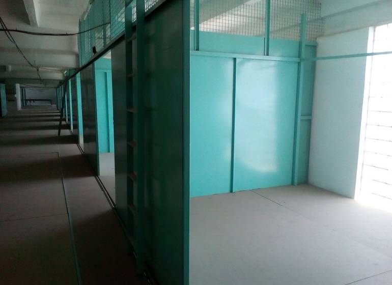 Sklad 16 m2 v stráženom areáli Stará Vajnorská - Chodba na ulici Stará Vajnorská vedľa skladov a hál s modrými kovovými úložnými jednotkami.
