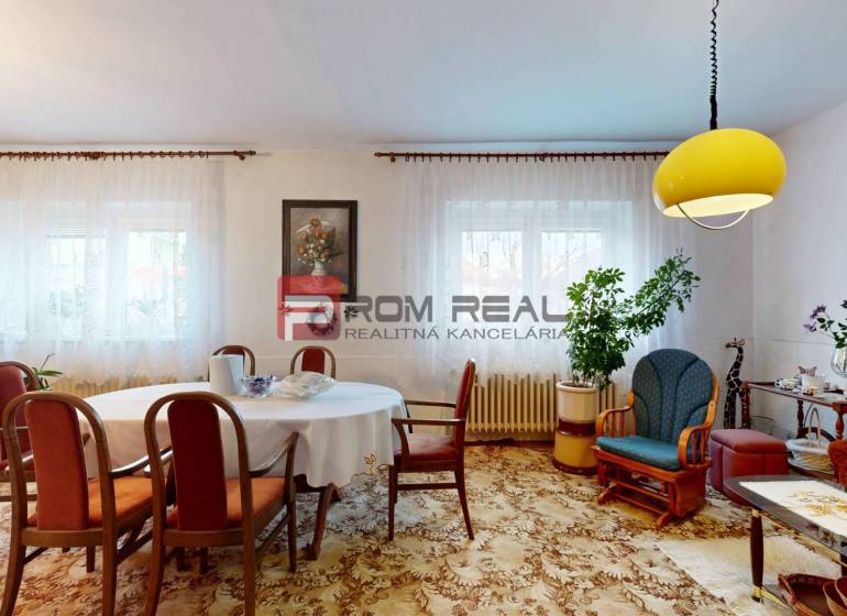 Na PREDAJ rodinný dom vo výbornej lokalite Bratislava - Ružinov - Obývacia izba v rodinnom dome so stolom, stoličkami, dekoráciami a žltým svietidlom na strope.