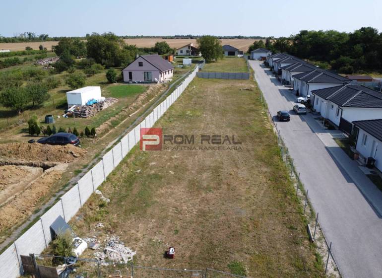Stavebný pozemok so stavebným povolením a projektom na dvojdom - Pozemky - bývanie v Štefanovej, vedľa prázdna parcela, obklopené vidieckymi domami a zeleňou.