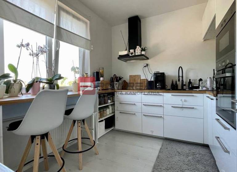 Na PREDAJ priestranný 3 izbový byt s balkónom v meste Senec - Kuchyňa v 3-izbovom byte s bielymi skrinkami a barovými stoličkami.