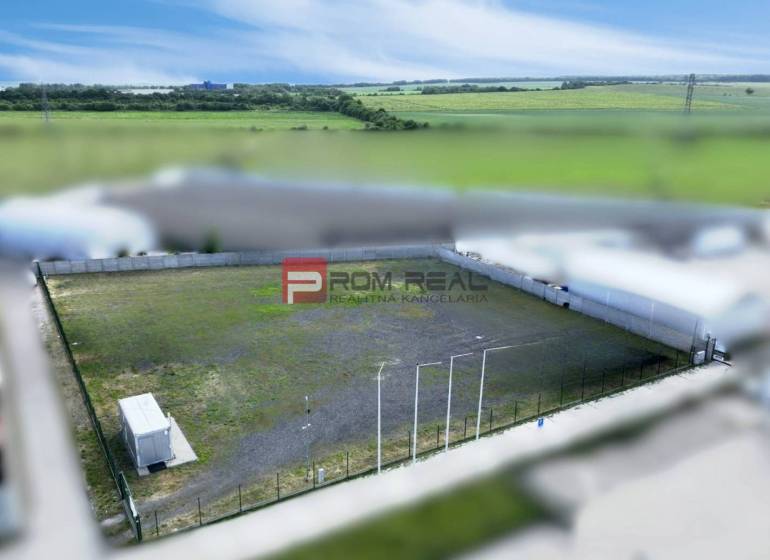 Prenájom spevnenej plochy - parking, skladovanie, Pezinok - Výrobné priestory v Pezinku s oploteným vonkajším priestorom a kontajnerom, obklopené poľami.