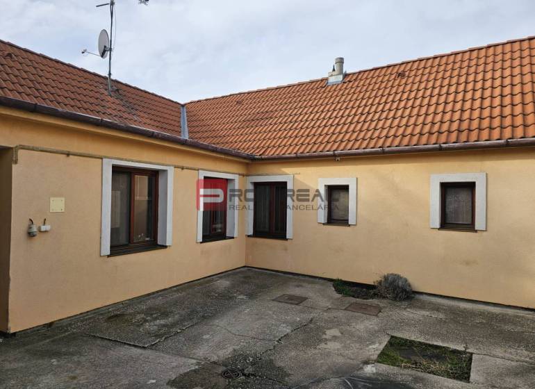 Rodinný dom na predaj Pezinok na skok od centra - Dvor rodinného domu na Slnečnej ulici v Pezinku s betónovou dlažbou a oranžovou fasádou.