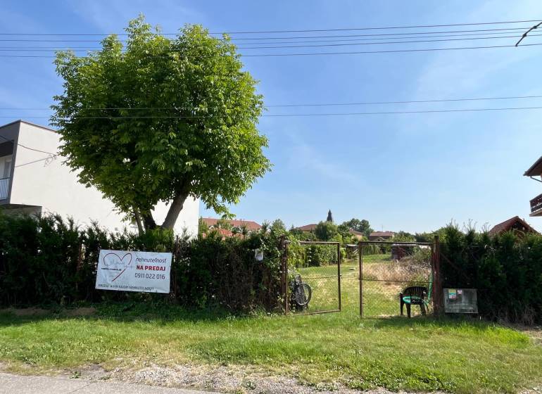 Stavebný pozemok s veľkou záhradou a potenciálom - Pozemky - bývanie v obci Dolný Bar, oplotený pozemok so stromom a bránou.
