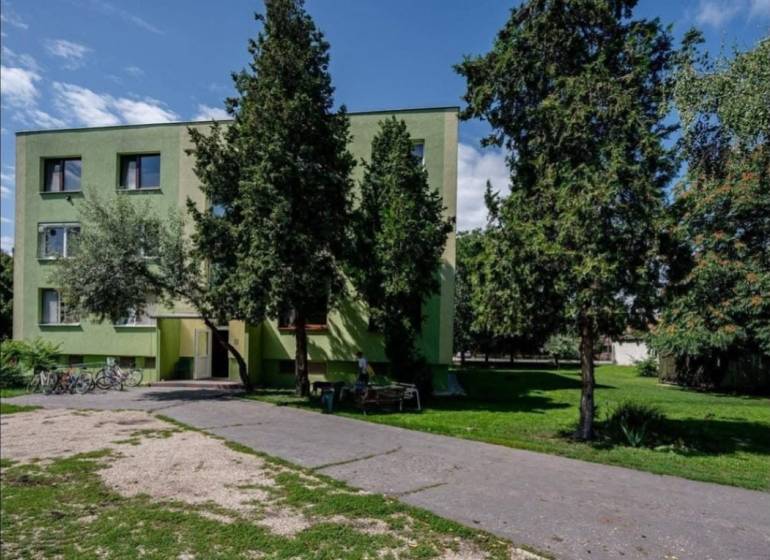NA PRENÁJOM 1,5-IZBOVÝ BYT S PIVNICOU, ČÍČOV - Bytovka obklopená stromami v Číčove, vedľa asfaltovej cesty a bicyklov.