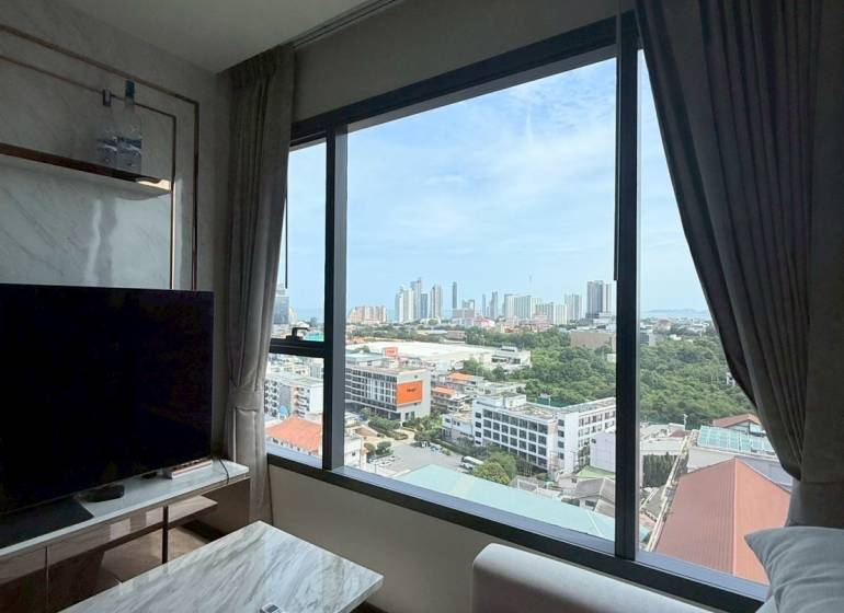 2 SPÁLŇOVÝ APARTMÁN ONCE PATTAYA - Obývačka 3-izbového bytu s výhľadom na mesto, pohodlným gaučom a TV stolíkom.