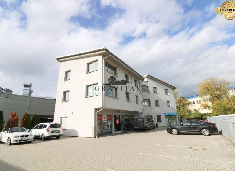 Samostatná kancelária 19,16 m2 - Lamačská cesta - Budova na ulici Lamačská cesta so zaparkovanými autami, kancelárie na prízemí, oblačné nebo.