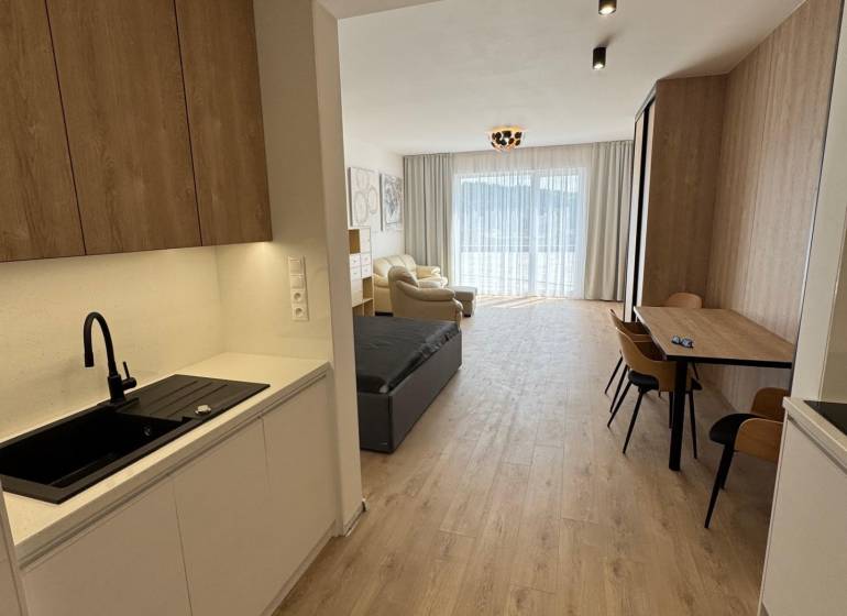 Prenájom NOVOSTAVBA FIM moderný byt 50 m2 + terasa 53 m2 PB - Kuchyňa v 2-izbovom byte s drevenými podlahami, drezom a jedálenským stolom.