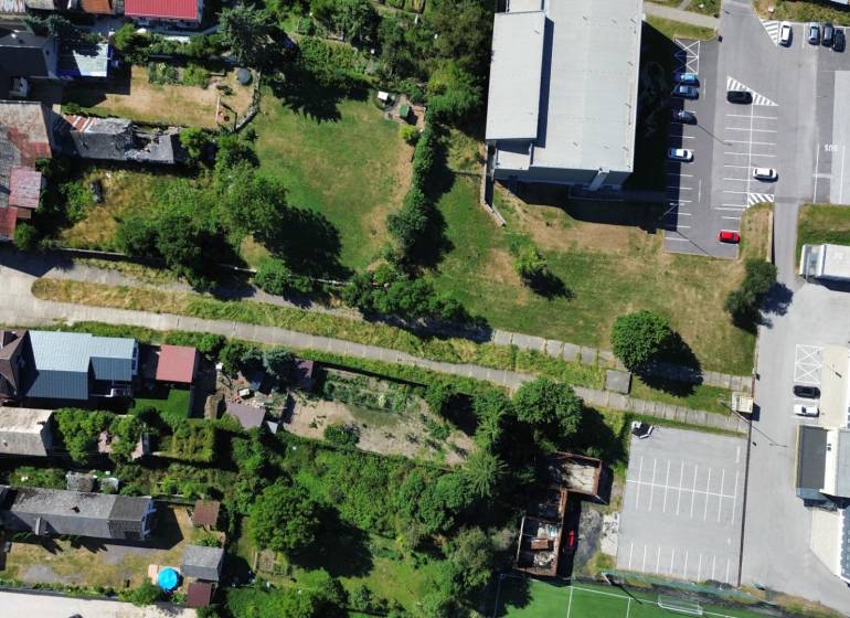 SLOVREAL predaj pozemku Žiar nad Hronom - Letecký pohľad na pozemky pre bývanie v Žiari nad Hronom s cestou a parkovaním.