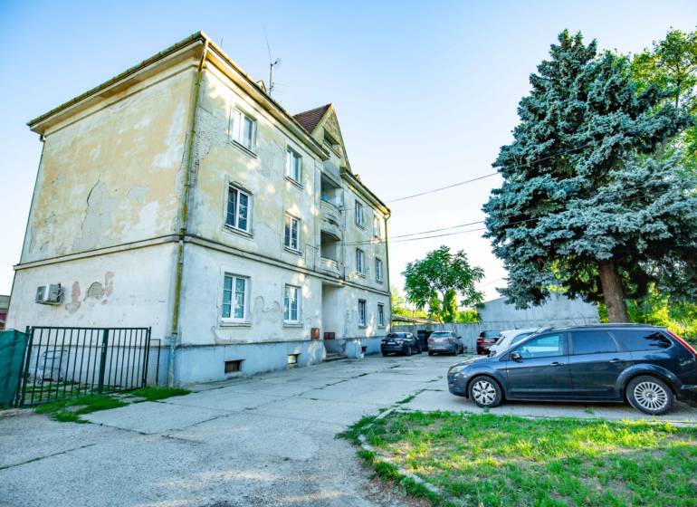 3 IZBOVÝ BYT 89,14 m2 VHODNÝ NA REKONŠTRUKCIU, ALE OBÝVATEĽNÝ UŽ TERAZ - Exteriér bytovky na Nobelovej ulici v Trnave s parkoviskom pre 3-izbový byt.