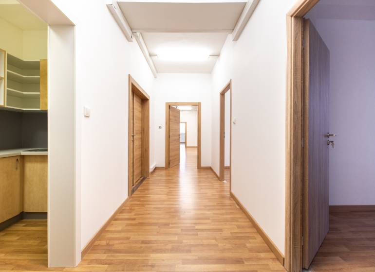 Klimatizované kancelárske priestory v areáli na Pestovateľskej ulici - Chodba s drevenou podlahou a dverami v kancelárii.