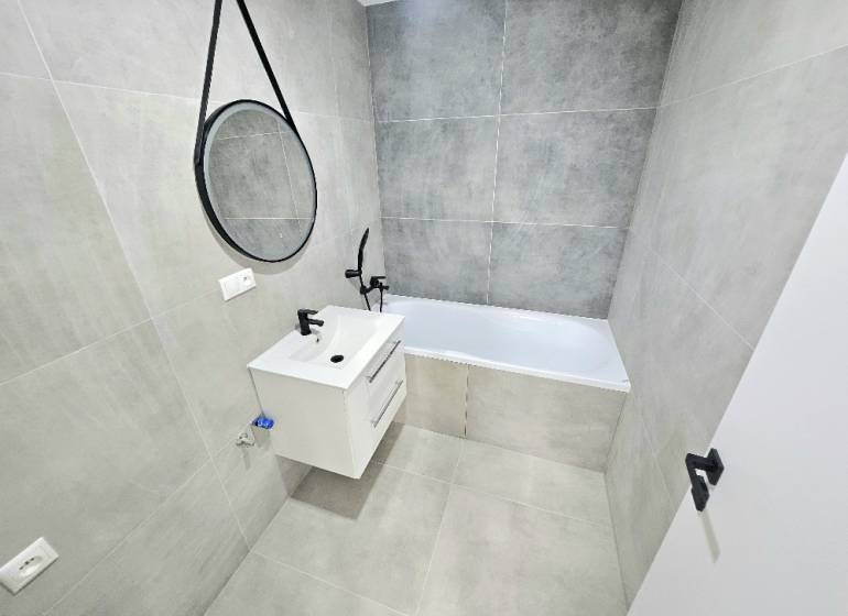 3 izbový byt Bánovce nad Bebravou / CENTRUM- STRED / 56 m2 / NOVÁ REKO - Kúpeľňa v 3-izbovom byte s vaňou, umývadlom a zrkadlom na stene.
