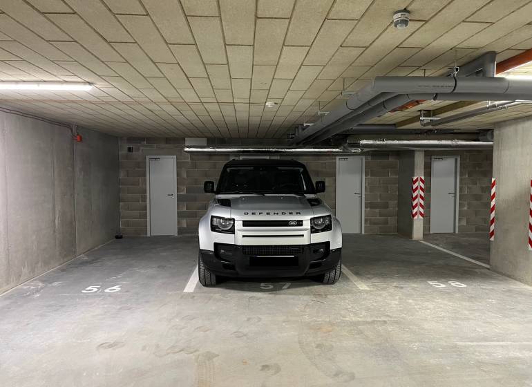 PARKOVACIE STÁTIE + KOBKA - PRI ŠAJBÁCH, BRATISLAVA - RAČA - Auto parkujúce v garáži s dverami a číslovaním na podlahe.