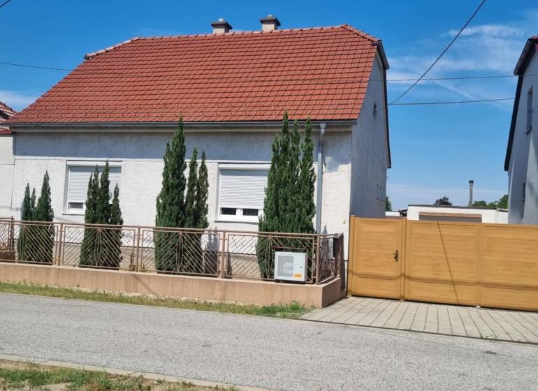 Rodinný dom na predaj - Malacky. - Rodinný dom na ulici Písniky v Malackách, biela fasáda, červená strecha, tuje pri plote.