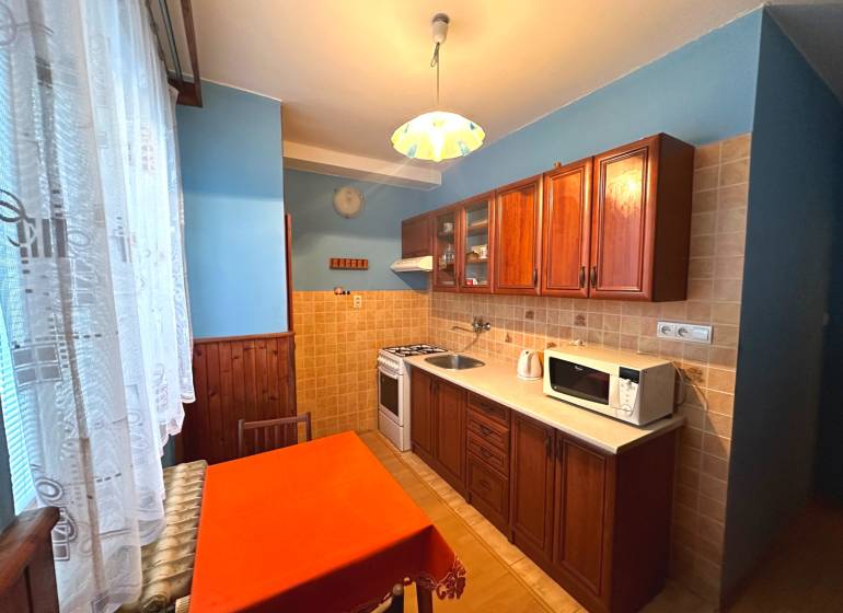 PRENÁJOM - 3 izbový byt s balkónom, Šafárikova ulica, Rožňava - Kuchyňa v 3-izbovom byte s drevenými skrinkami a jedálenským stolom.