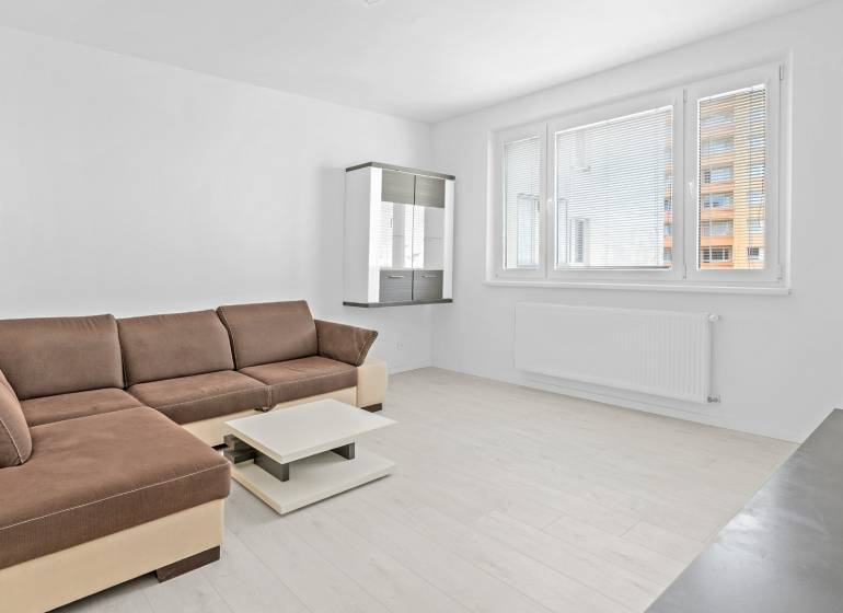 Moderný, zrekonštruovaný 3i byt 68m2, s lodžiou, pivnicou a parkovaním - Svetlá obývačka s rohovou pohovkou v 3-izbovom byte, s výhľadom na panelák.