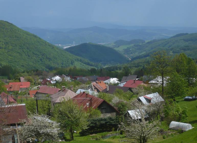CHATA KORDÍKY - 2 poschodia, 3 izby+kuchynka, kúpelňa - 420 m2 pozemok - Pohľad na chaty v Kordíkoch pri Banskej Bystrici s malebnými kopcami v pozadí.