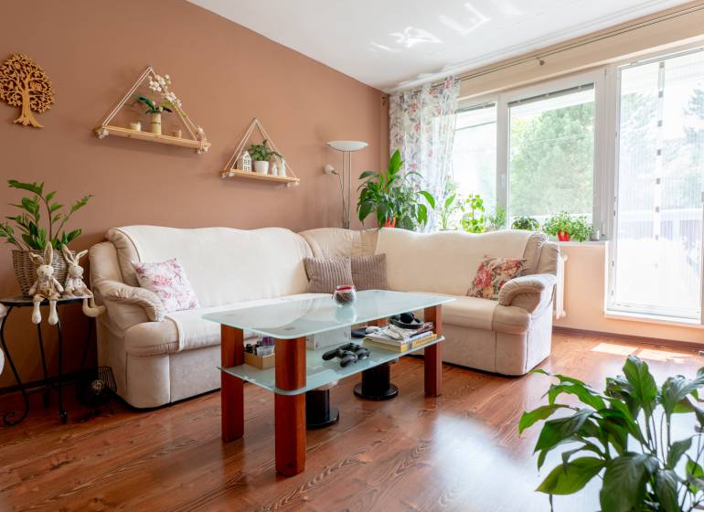 SVETLÝ – 3i s balkónom 69 m² – TOP lokalita Nová Dubnica - Svetlý obývací priestor v 3-izbovom byte s kvetinovou výzdobou a pohodlnou sedačkou.