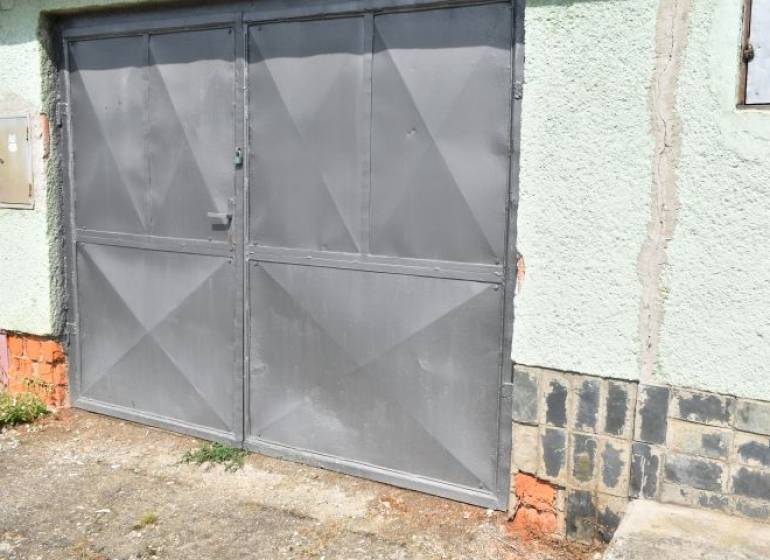 Priestranná garáž s montážnou jamou a elektrinou na Letnej v Rožňave - Šedá kovová brána na garáži na Letnej ulici v Rožňave.