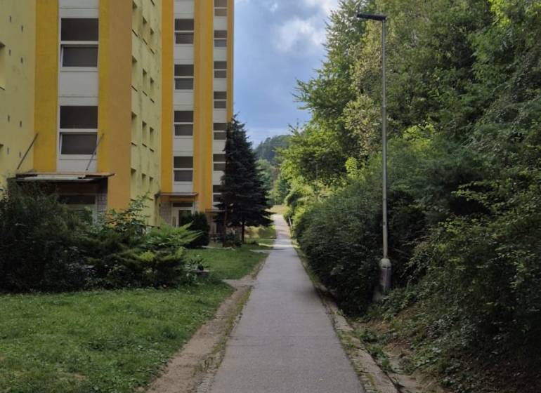 3i byt ul. Moskovská, Banská Bystrica - Žltý bytový dom na Moskovskej ulici v Banskej Bystrici vedľa chodníka a zelene.