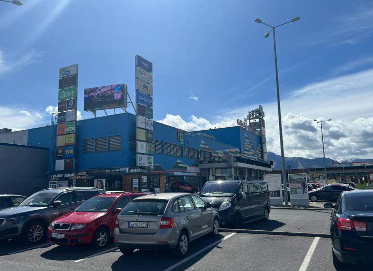 Prenájom obchodných priestorov v nákupnom centre RGB Liptov - Na ulici Kamenné pole, parkovisko pred obchodnými priestormi s výhľadom na hory.