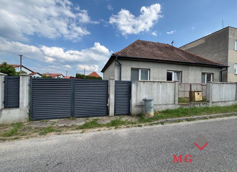Rodinný dom Solčany - Rodinný dom v Solčanoch na ulici ini s plotom a bránou.