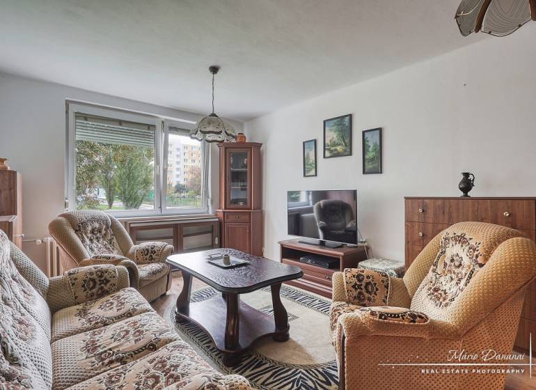 3-izbový byt v Šali na Vajanského ulici - Obývacia izba v 3-izbovom byte s pohovkou, kreslami a podlahou s dreveným dekorom.